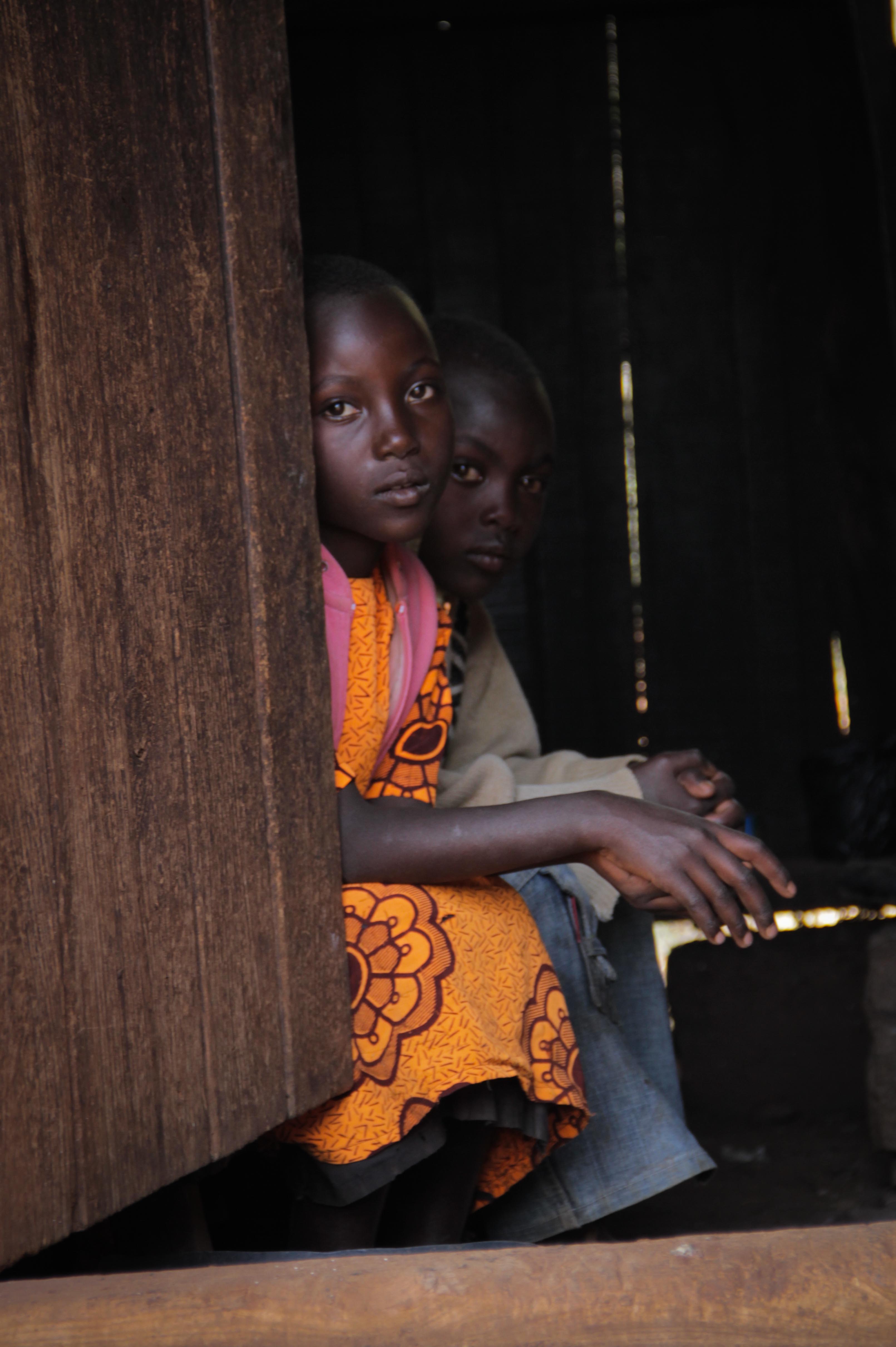 Zipporah's younger sister and brother sit in the shade of their kitchen.